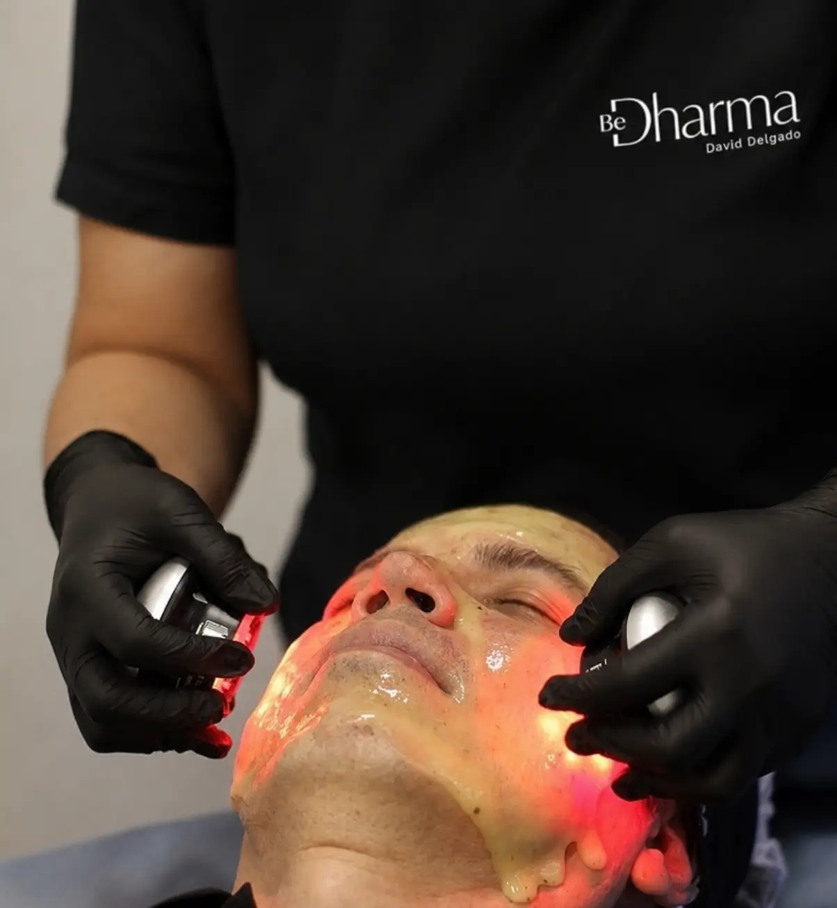 Man receiving a facial skin treatment with red light therapy at Clínica Be Dharma in Medellín