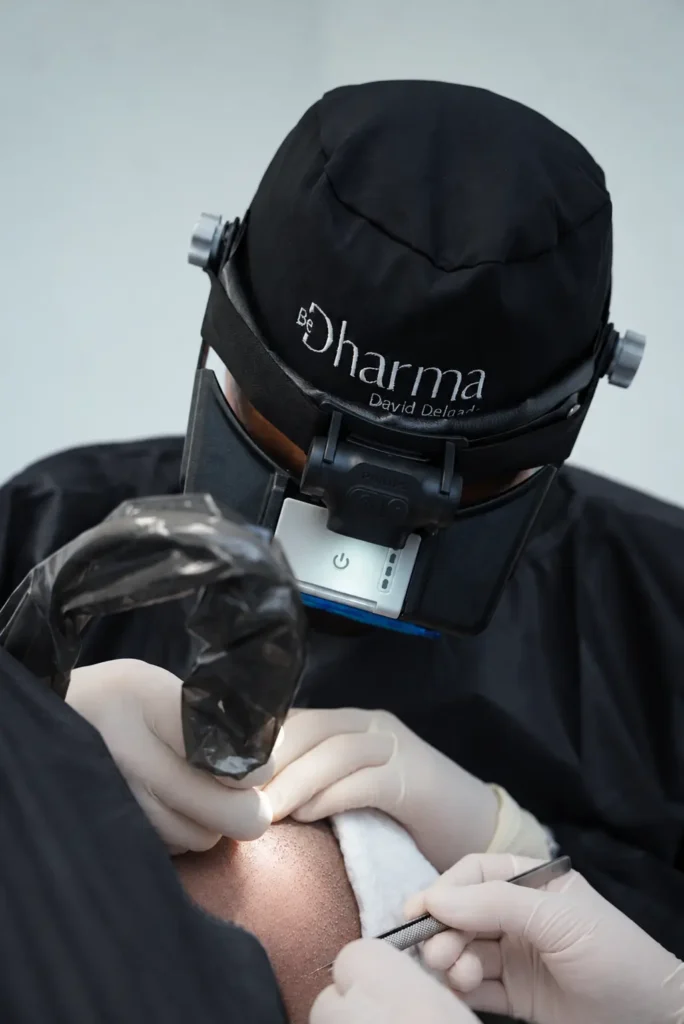 Médico especialista realizando un implante capilar con técnica FUE manual en Clínica Be Dharma, Medellín, Colombia, utilizando instrumental de precisión